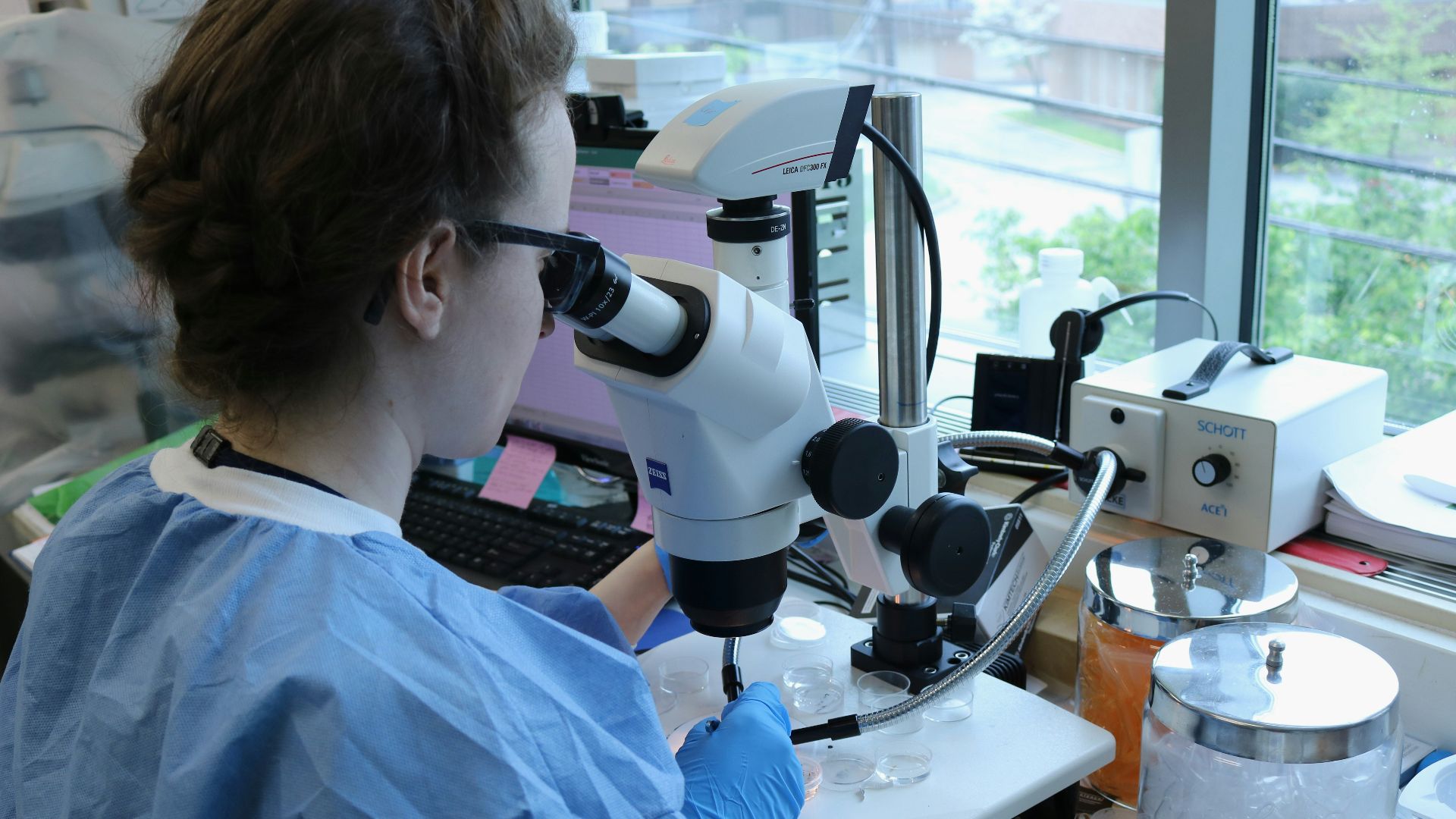 a woman in a lab coat looking through a microscope