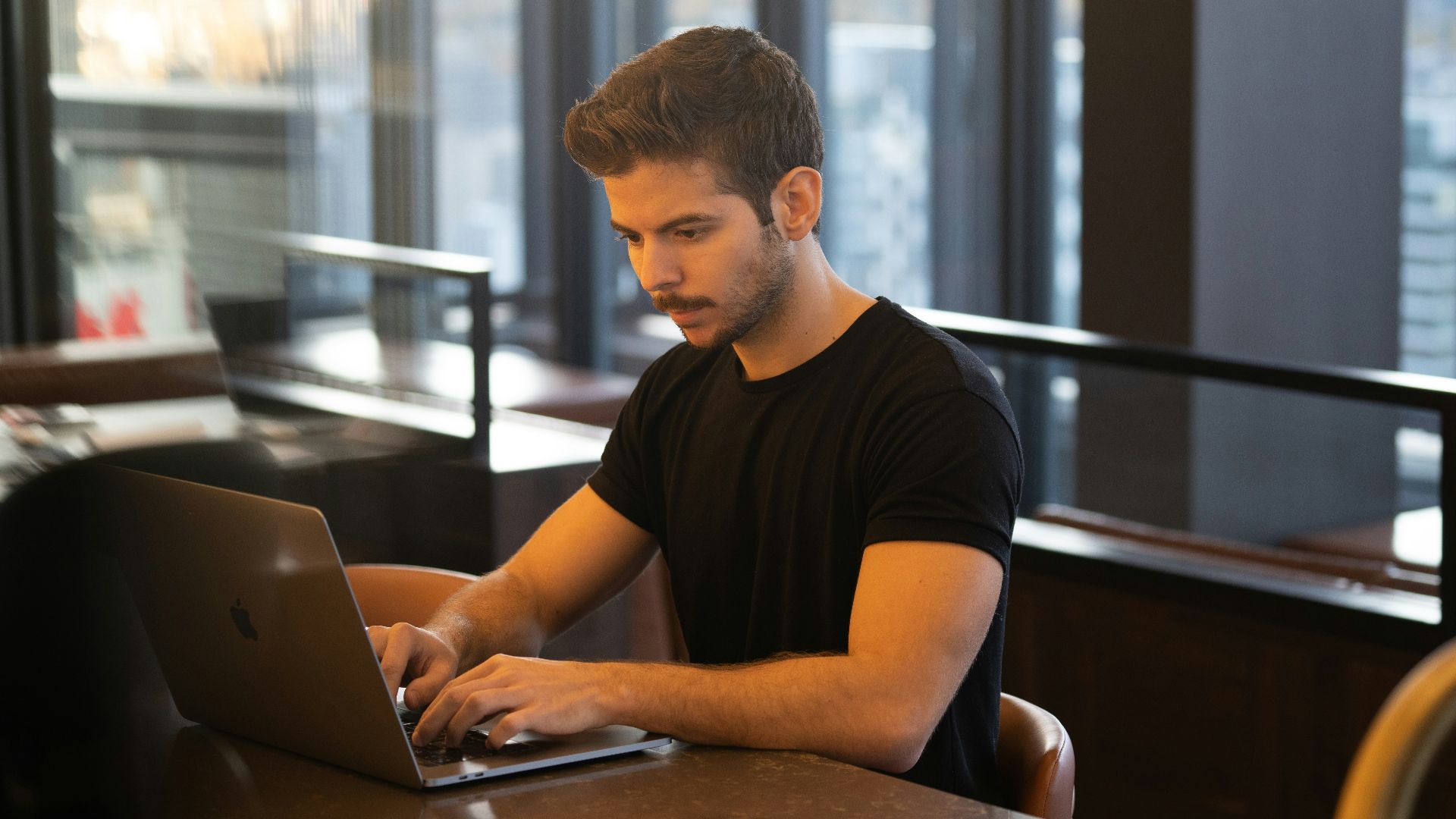 man in black crew neck t-shirt using macbook