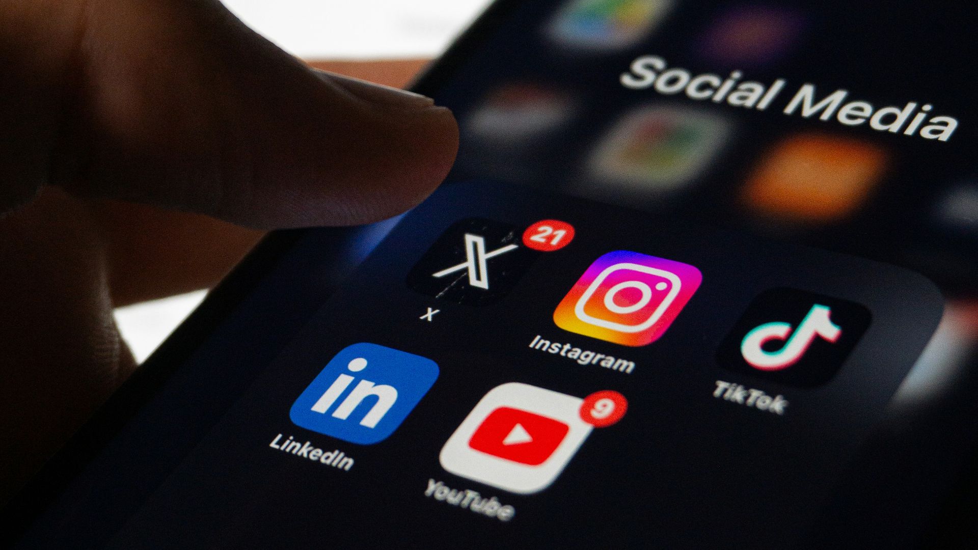 A person holding a smart phone with social media on the screen