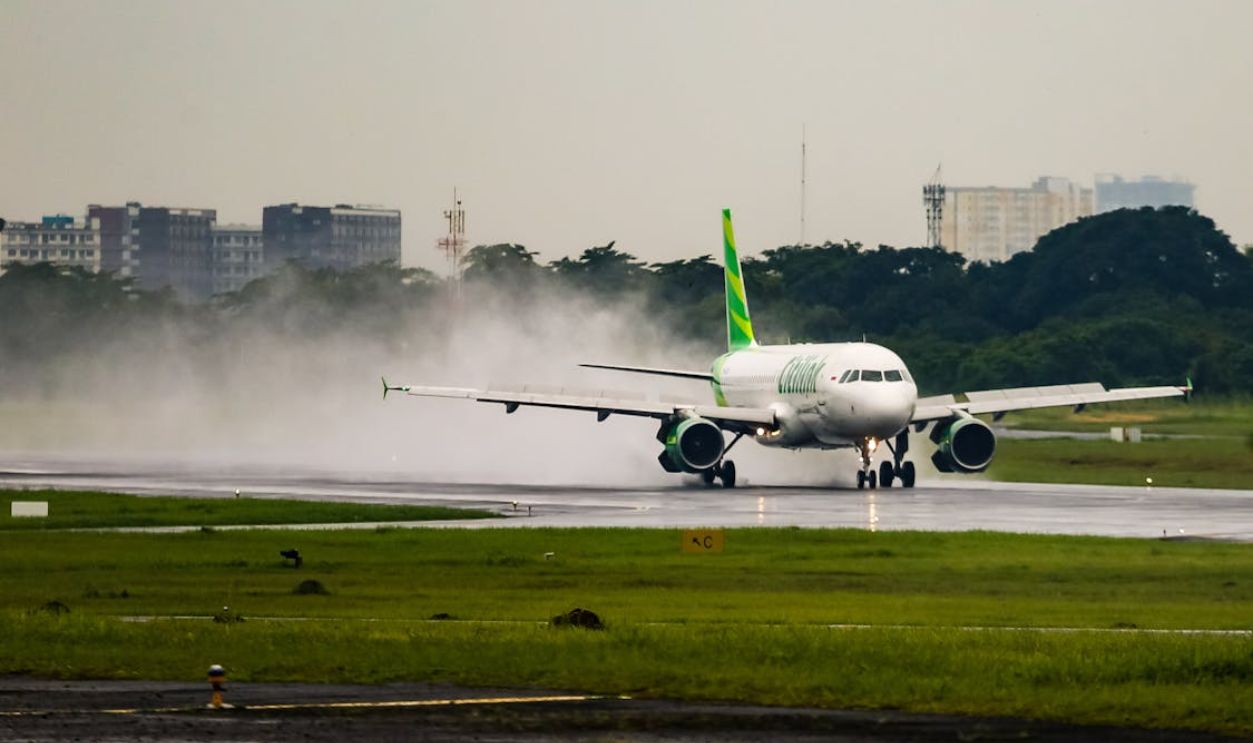 Passenger airplane lands on wet runway in Jakarta, Indonesia during daytime.