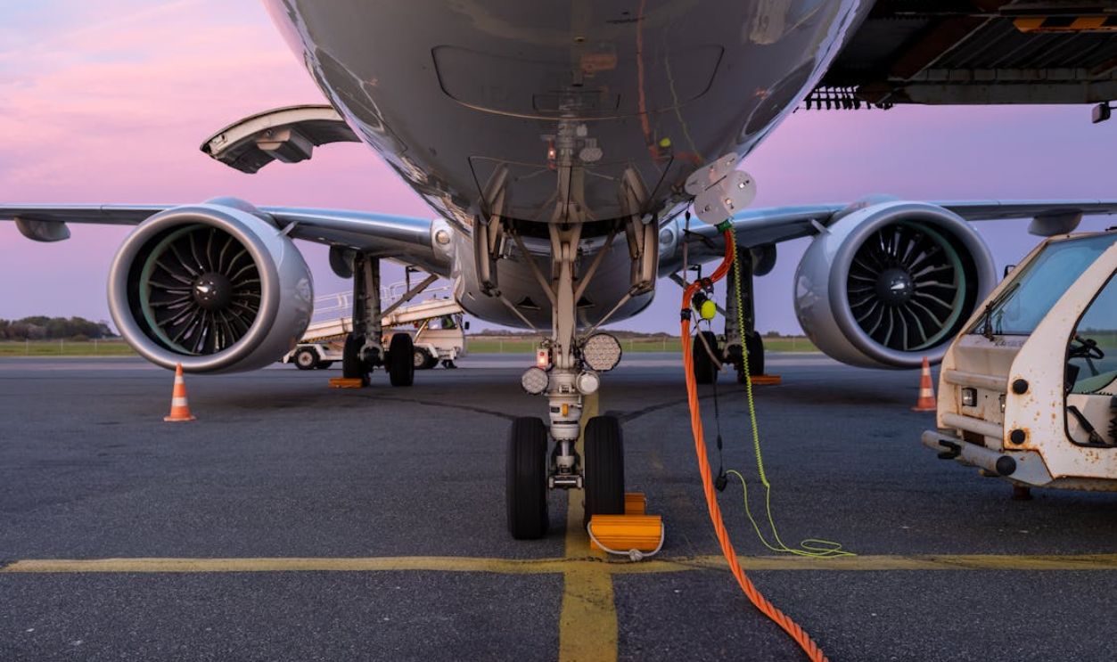 Close-up view of an airplane undergoing maintenance on the tarmac at sunset.