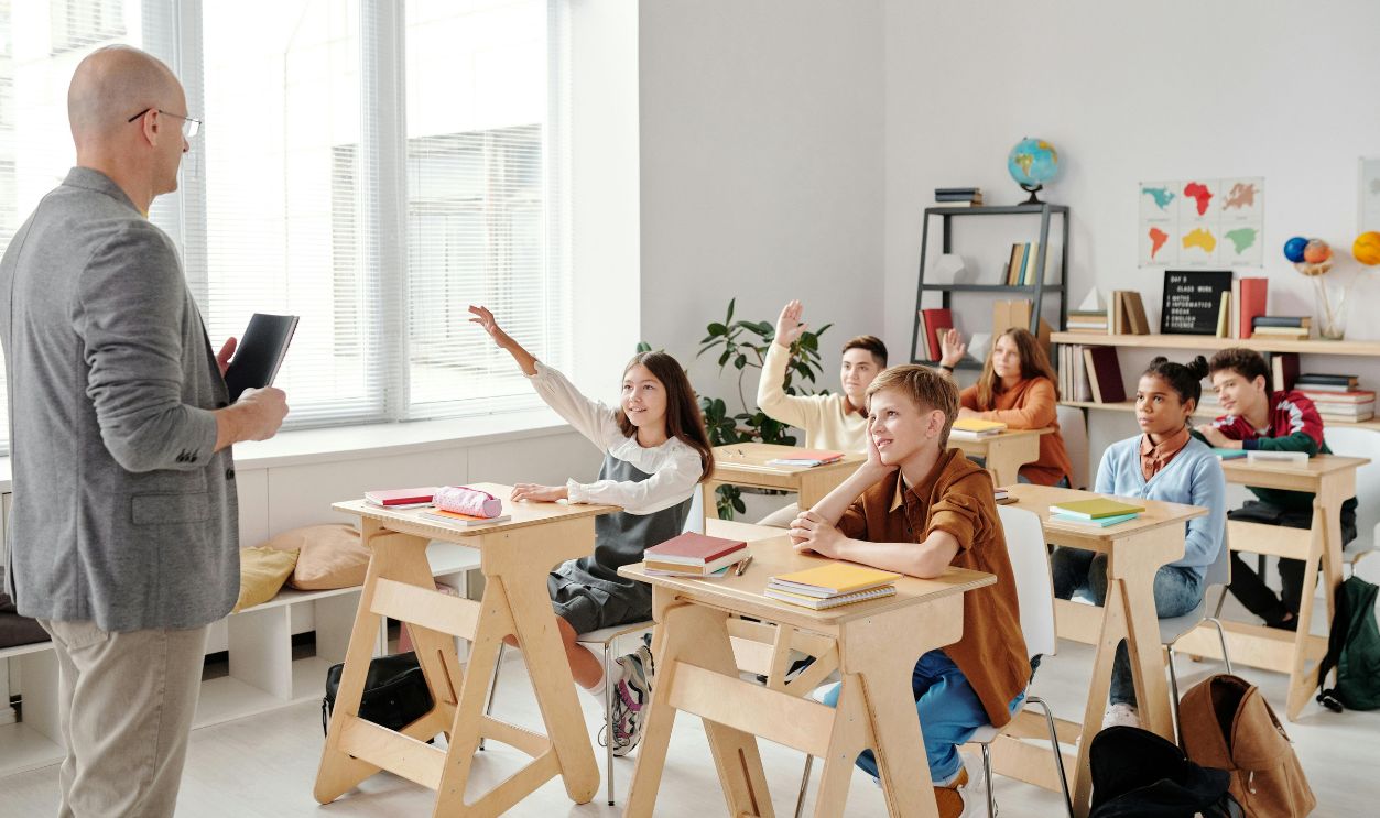 Students engage eagerly in a classroom, raising hands and participating in a lesson 