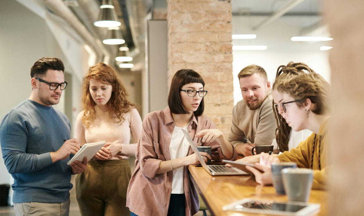 A diverse group of coworkers in a modern office engaged in teamwork using technology