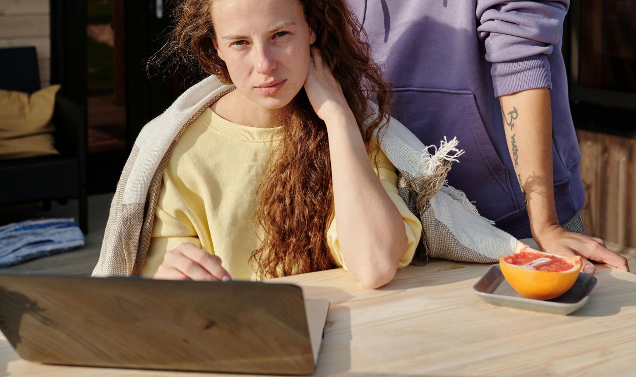 A smiling couple enjoying time together with a laptop on a sunny porch