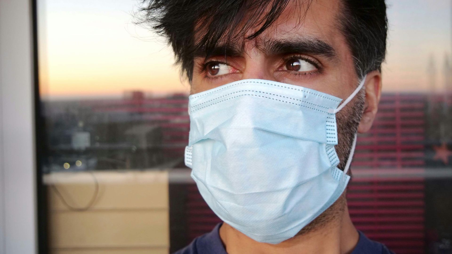 man in blue shirt wearing white face mask