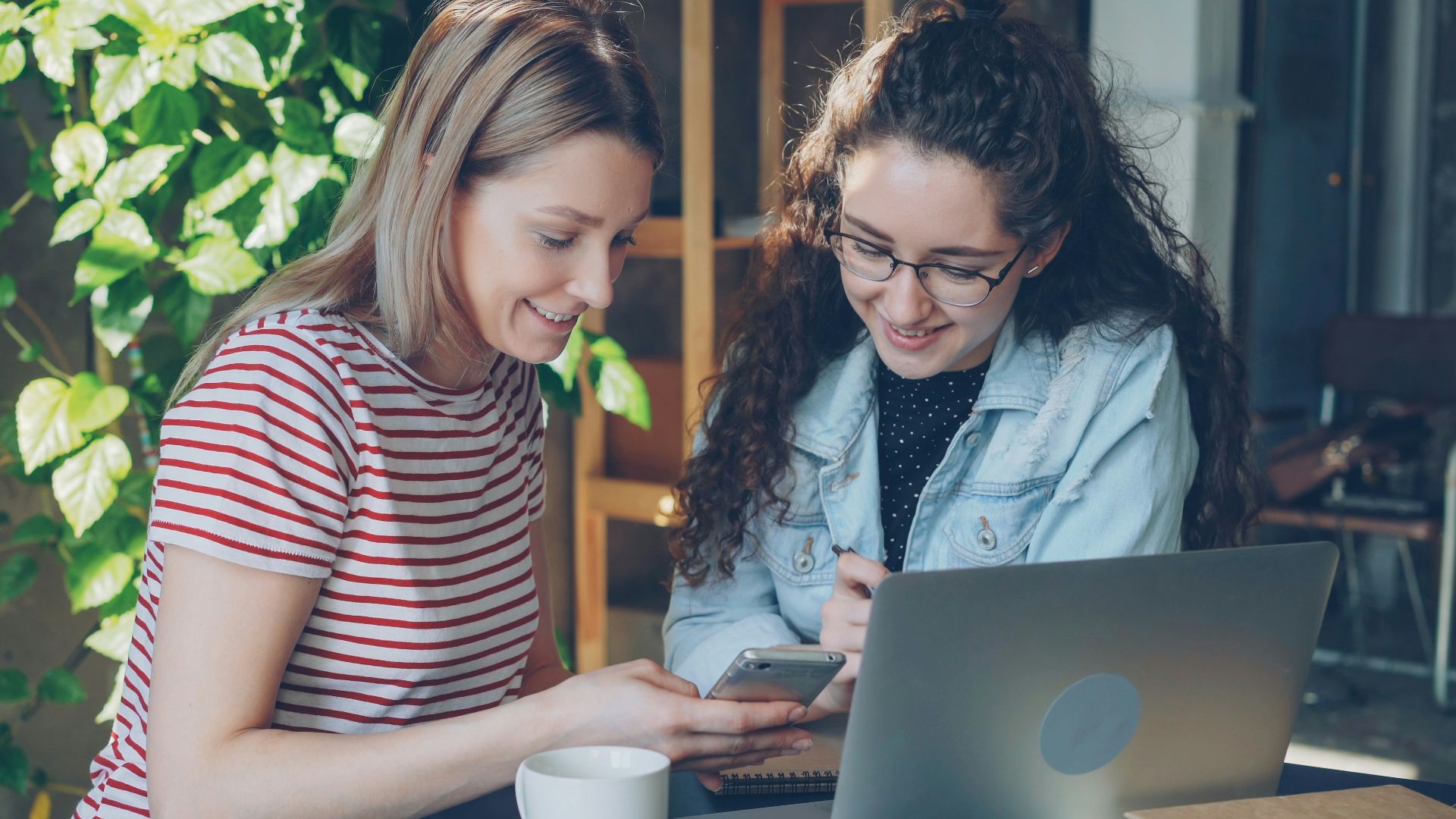 Two women collaborate on a laptop.