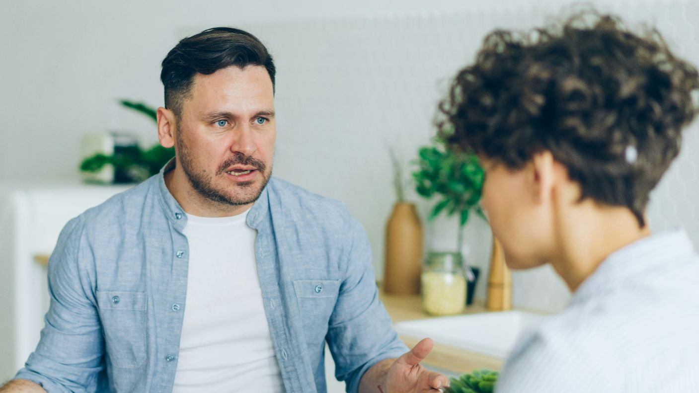a man sitting at a table talking to a woman