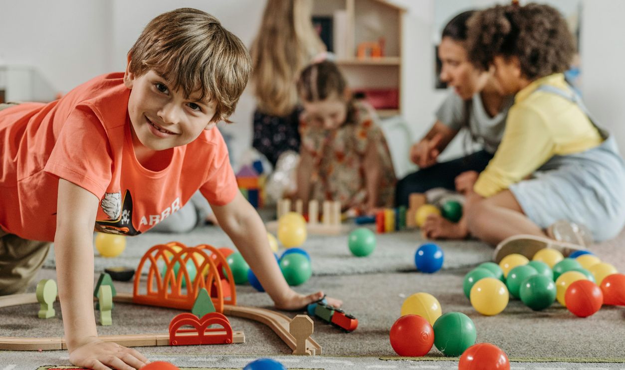 Happy children and a caregiver playing with colorful toys 