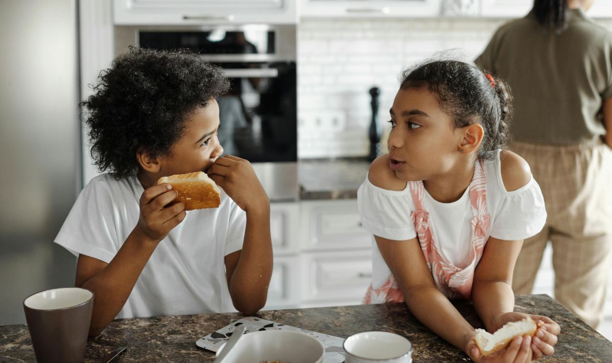 Two children enjoy breakfast together, talking and sharing moments