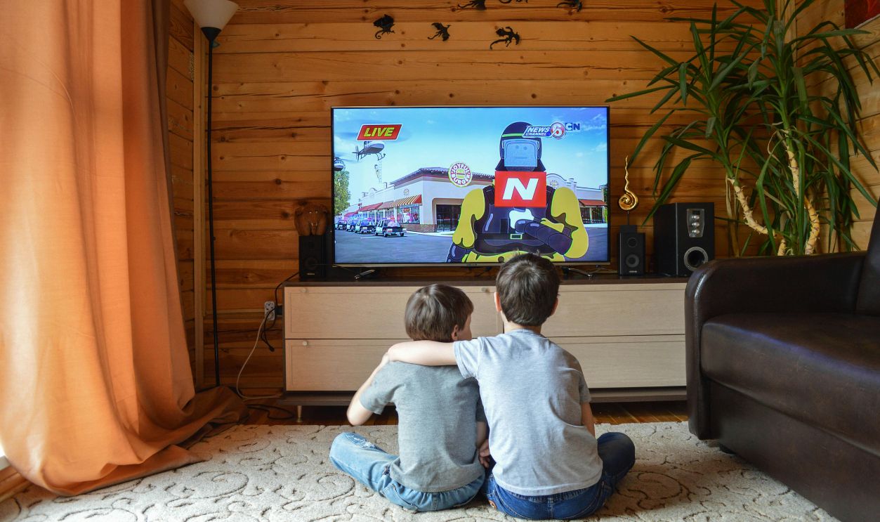 Two young boys enjoying animated show in cozy living room, emphasizing sibling bond