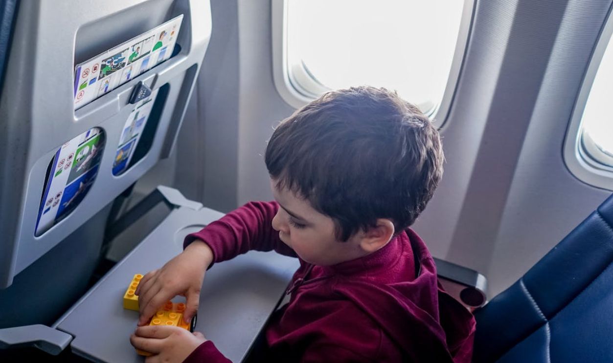 A young boy engrossed in playing with toy blocks on an airplane during a flight