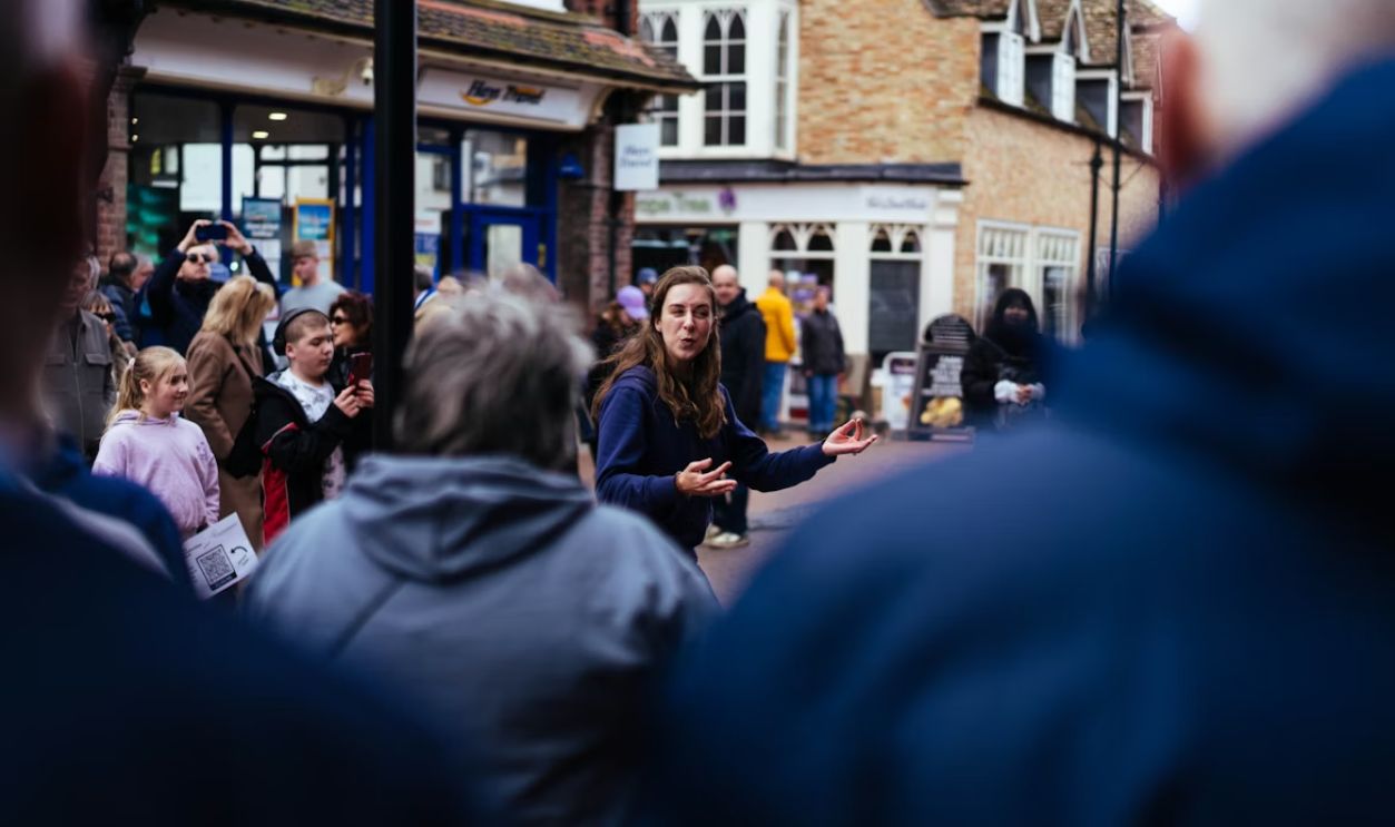 A woman speaks to a crowd on a street.