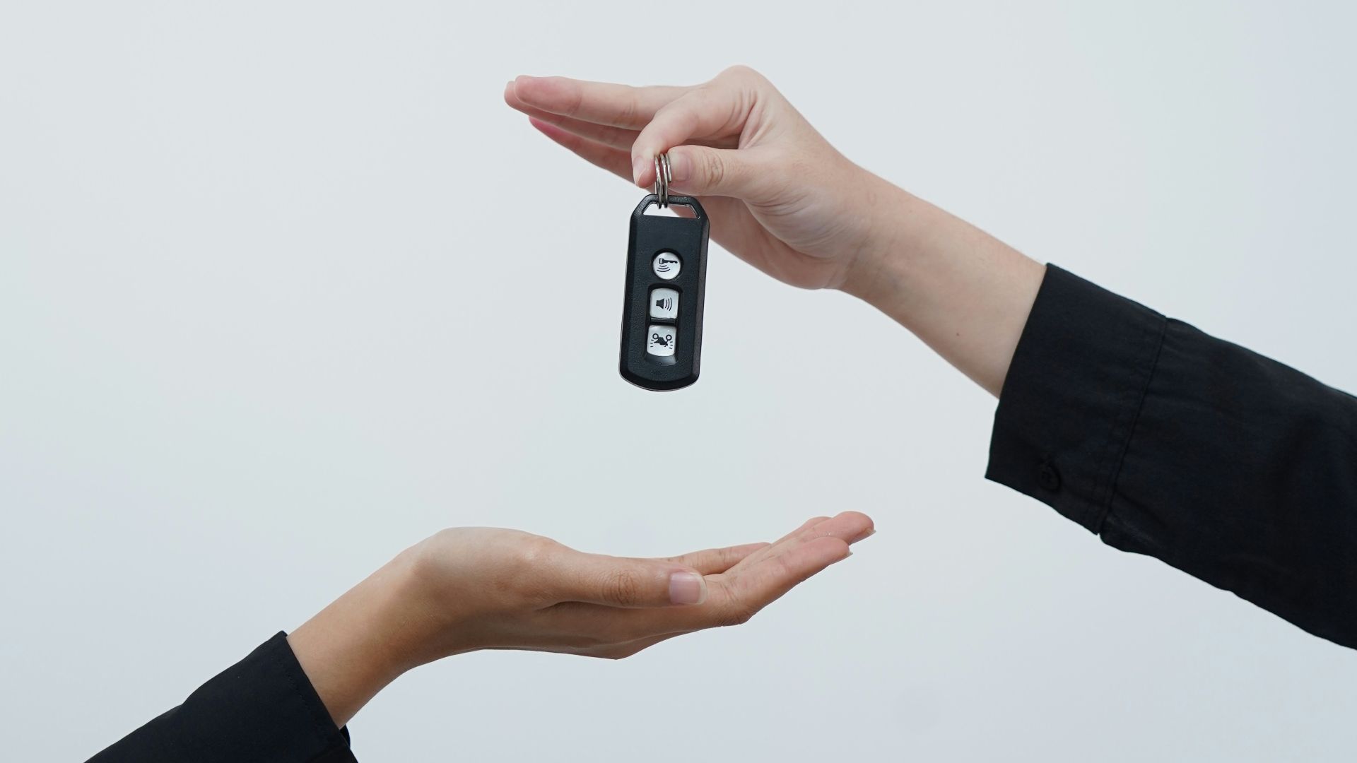 Hands exchanging a car key against a light background