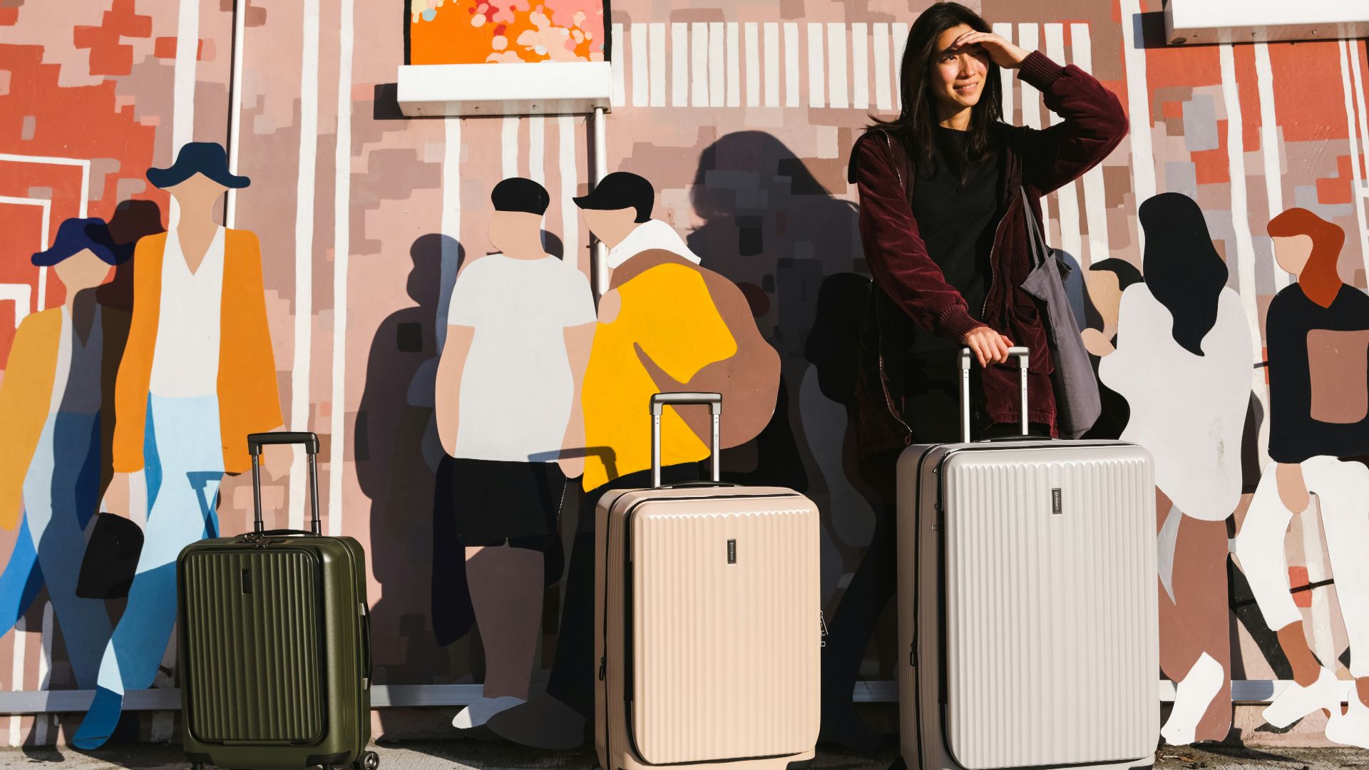 a woman standing next to two suitcases in front of a mural