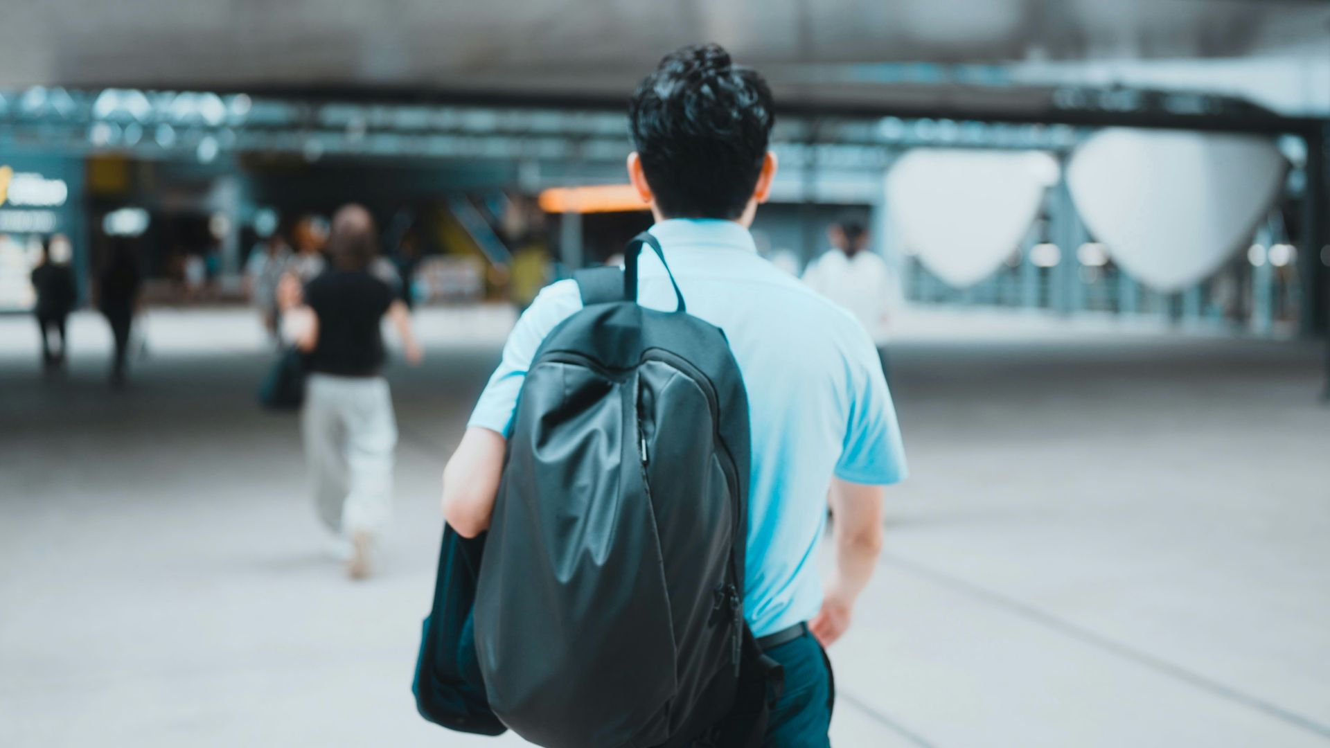 Man with backpack walks through modern building.