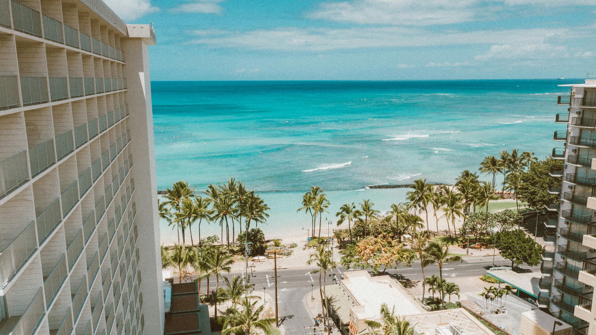 Breathtaking view of Waikiki Beach and palm trees from a hotel balcony in Honolulu, Hawaii.