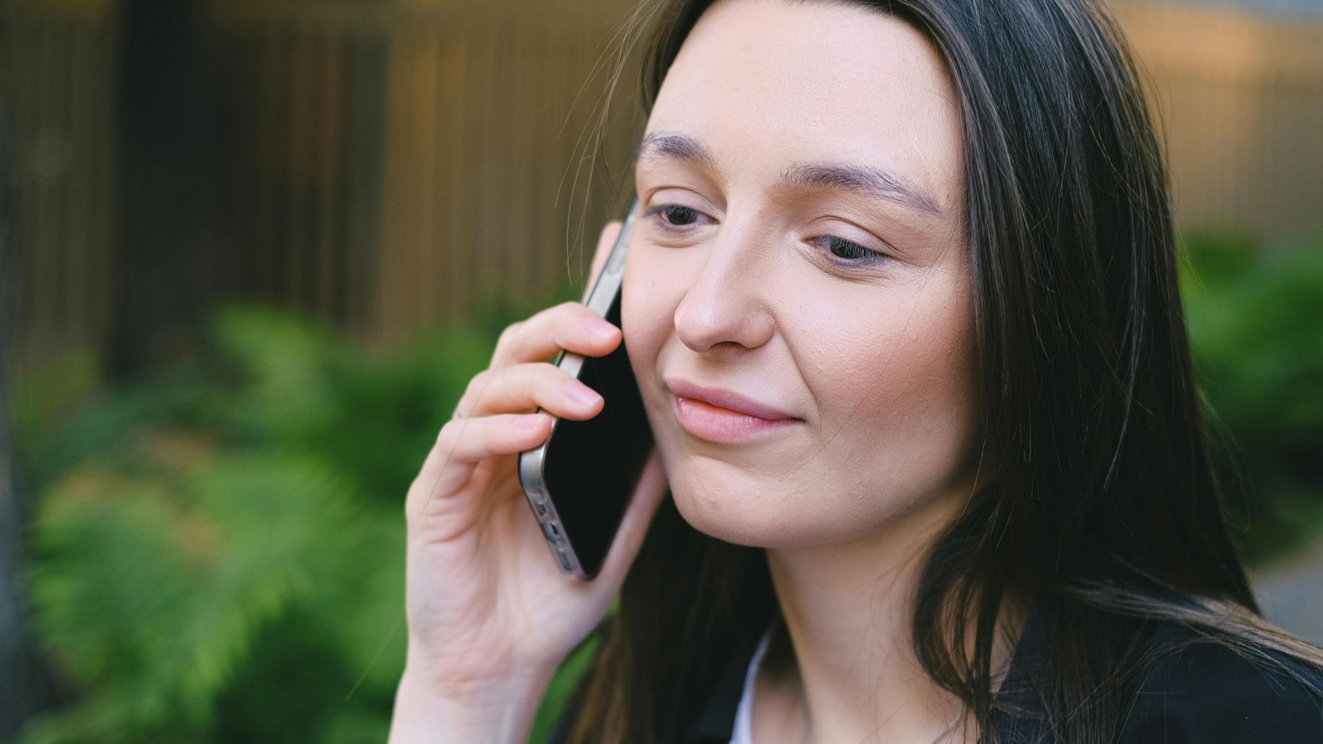 A young woman having a phone conversation in a serene outdoor setting, showcasing digital nomad lifestyle.