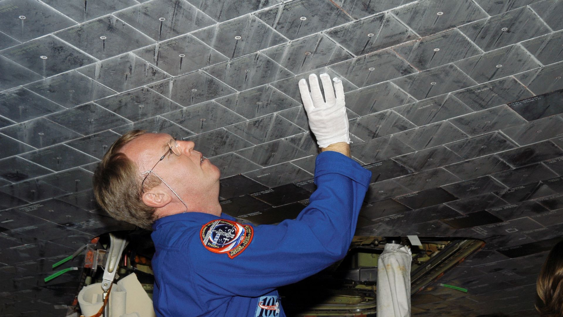JSC2003-E-61578 (30 October 2003) --- Astronaut Andrew S. W. Thomas, STS-114 mission specialist, takes a close look at tiles underneath the Space Shuttle Atlantis in the Orbiter Processing Facility at Kennedy Space Center (KSC).