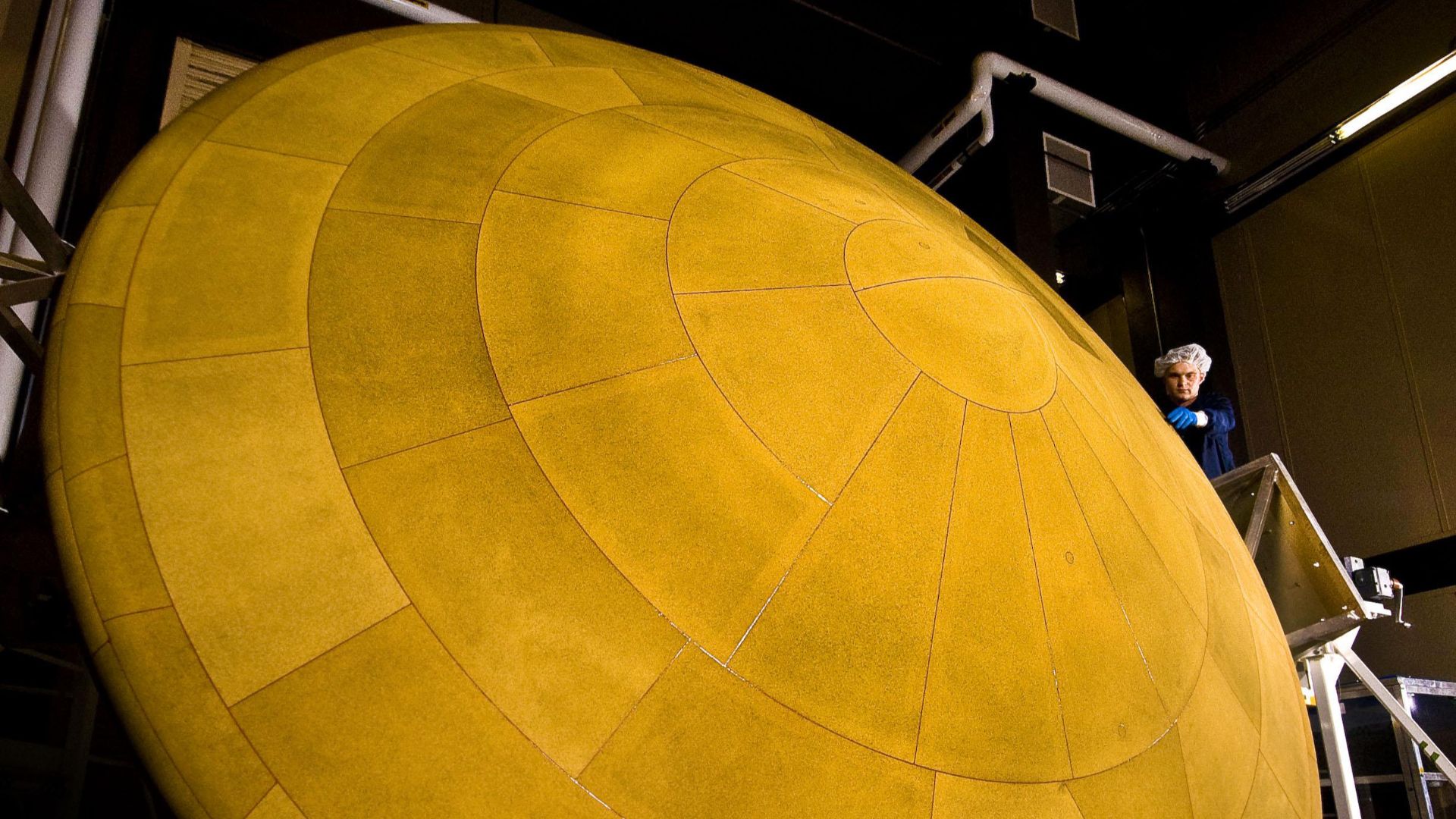 The finished heat shield for NASA's Mars Science Laboratory, with a diameter of 4.5 meters (14 feet, 9 inches), is the largest ever built for descending through the atmosphere of any planet. This image shows the heat shield and a spacecraft worker at Lock