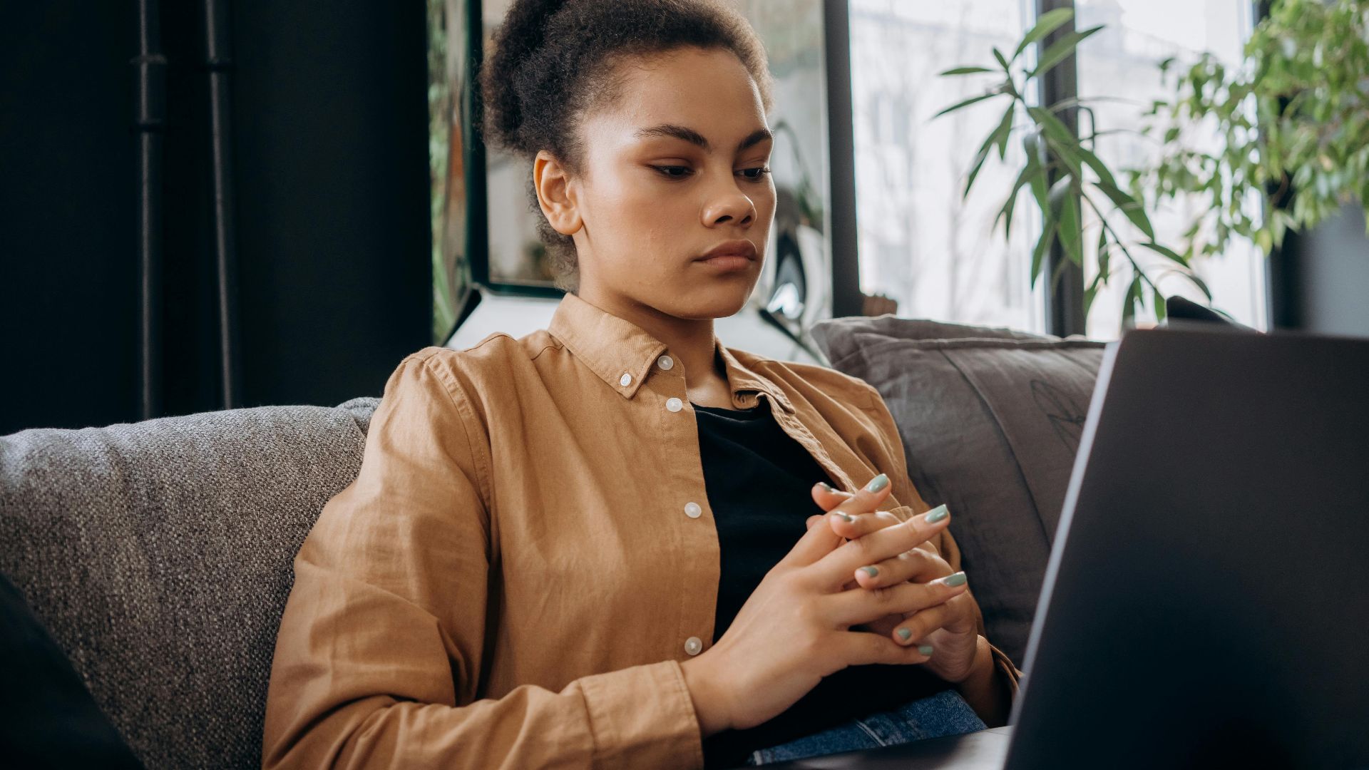 Young woman intently studying on a laptop while seated indoors with natural light.