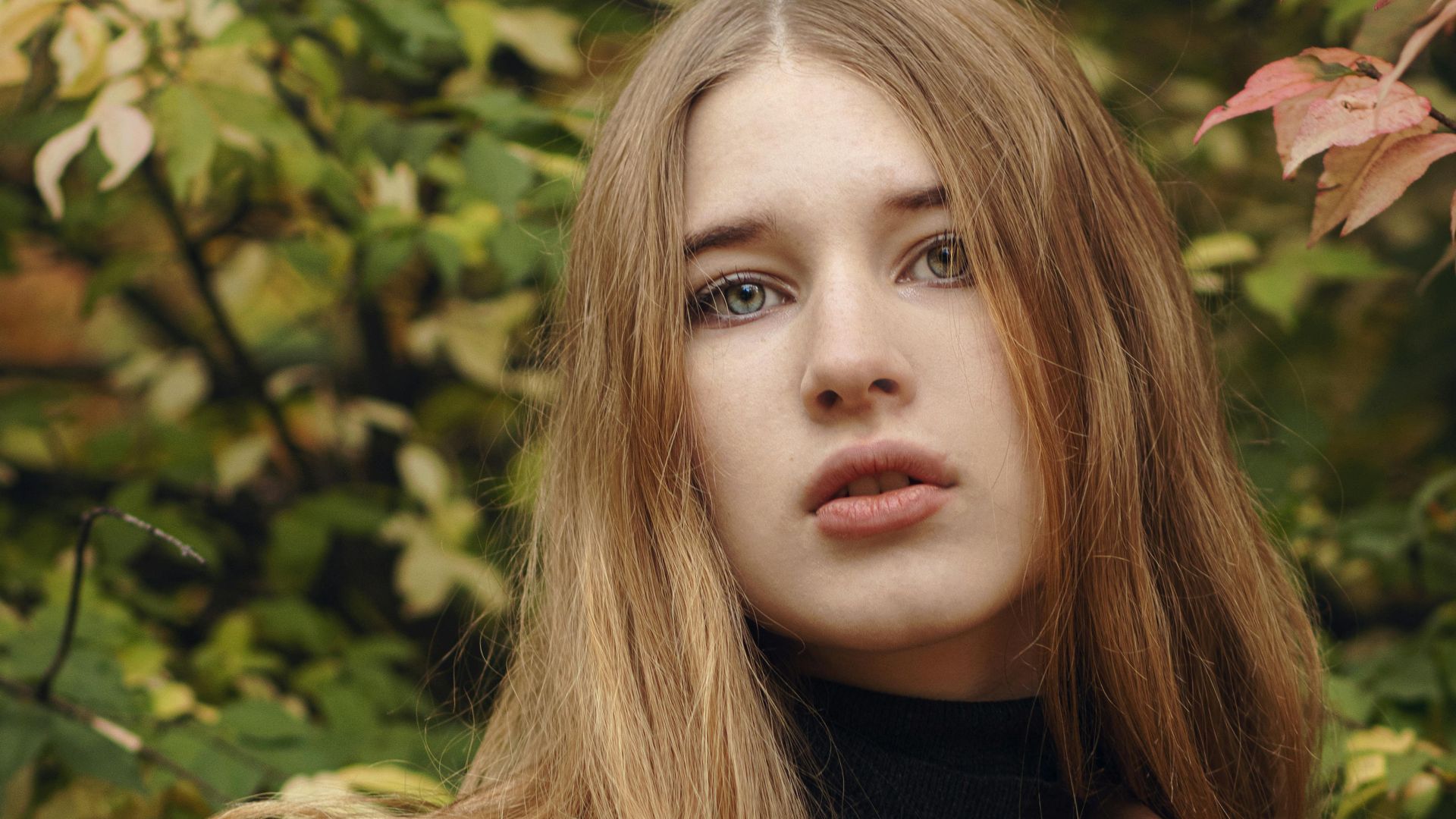 Young woman in fall fashion amidst lush foliage, showcasing autumn style.