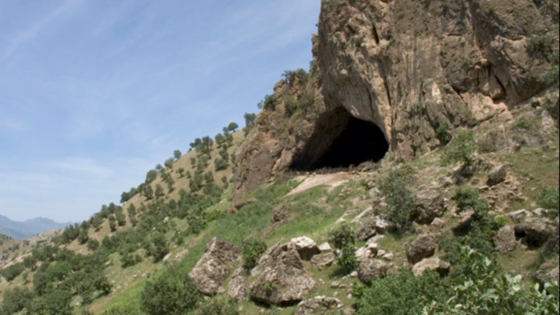 View of the exterior of Shanidar Cave, taken during the summer of 2005.  Note for scale the two crouching men in front of the cave.  At the time this photo was taken, the interior of the cave was being used as a pen by a local shepherd.

Licensing