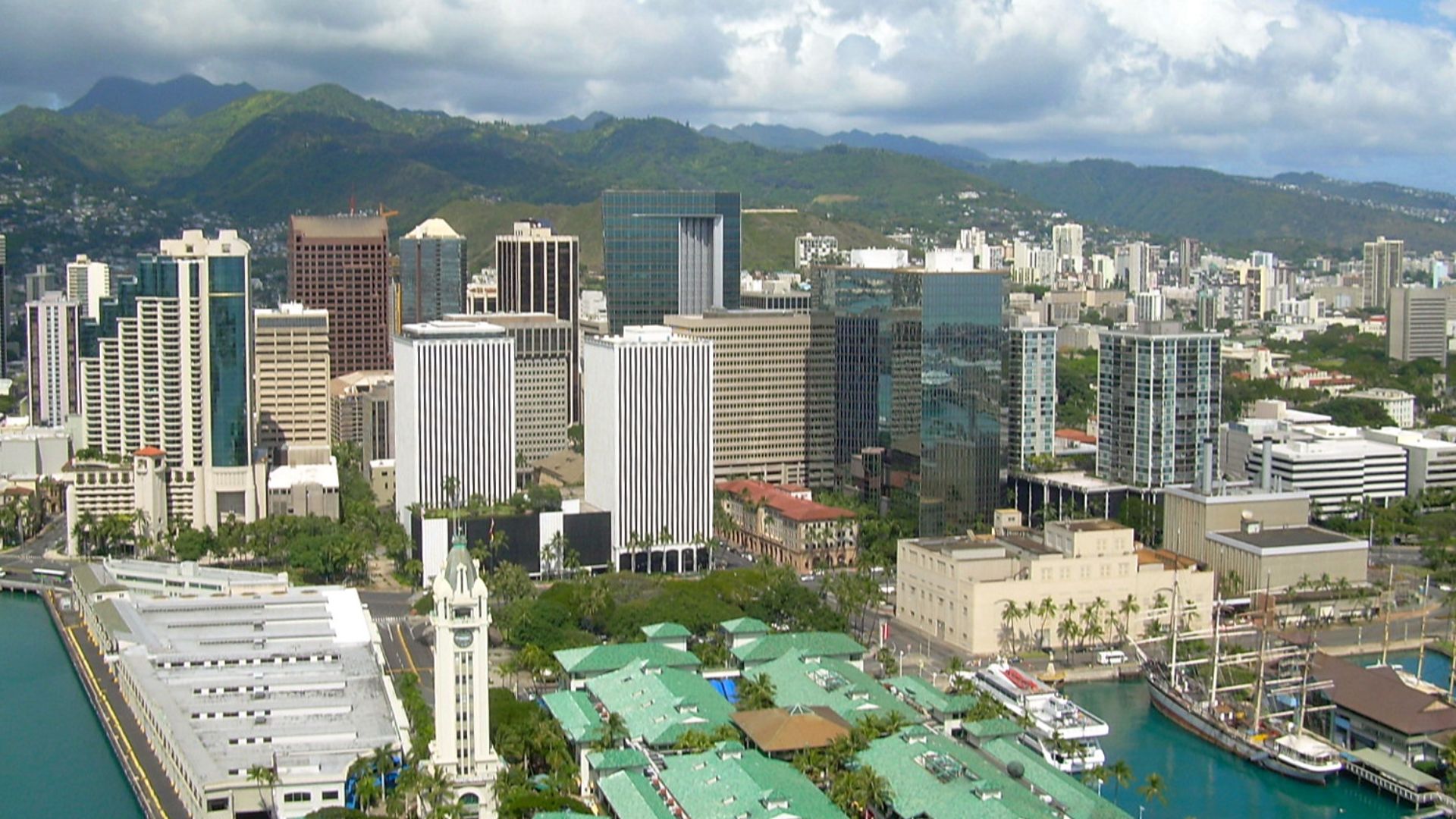An aerial view of downtown Honolulu, Hawaiʻi taken on April 7, 2007. In the foreground is Aloha Tower, a clock tower and lighthouse greeting visitors to Honolulu Harbor since 1926. In the center of the photo is First Hawaiʻian Center, the tallest building
