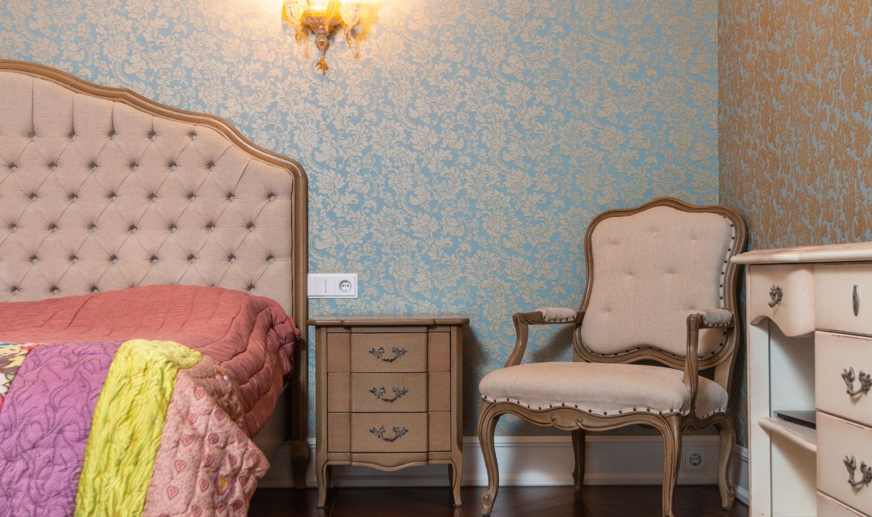 Chic bedroom decor featuring vintage furniture, patterned wallpaper, and cozy lighting