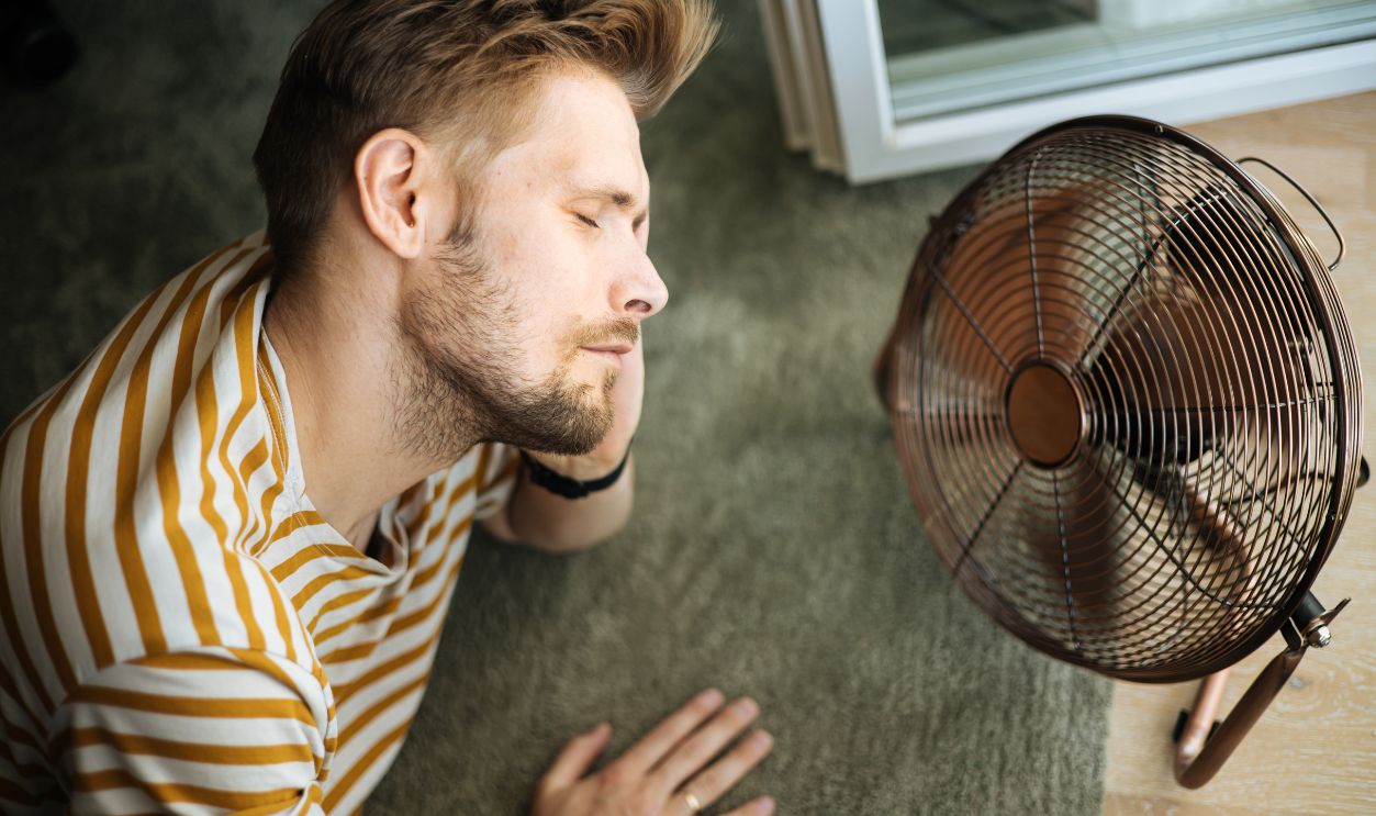During a summer heat wave, a man finds respite at his home desk with the help of an electric fan. A man beats the summer heat wave by finding relief with an electric fan