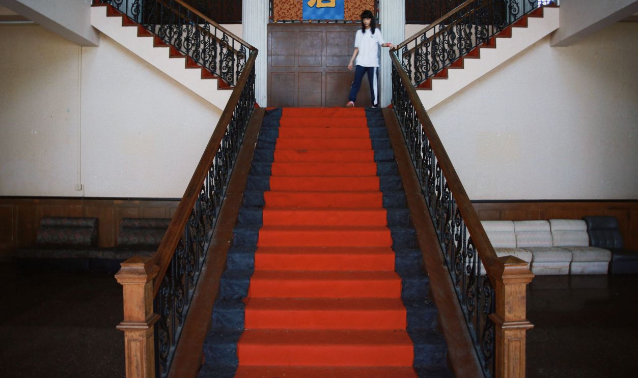 Symmetrical staircase with red carpet and Chinese script in a grand hall interior