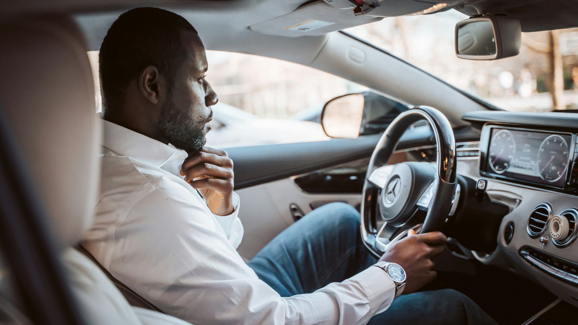 man in white dress shirt driving car during daytime