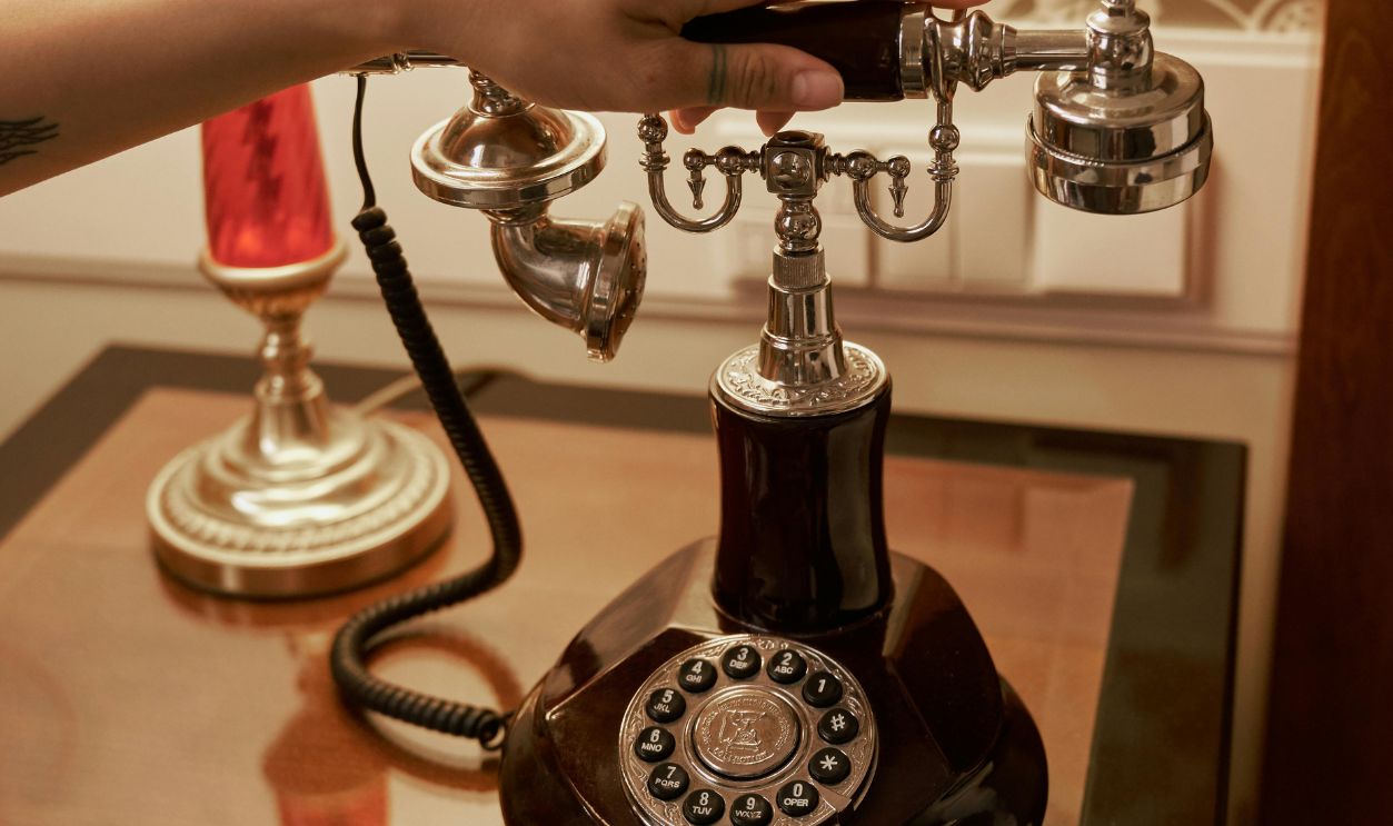 Close-up of a vintage rotary phone with a hand picking up the receiver in a luxurious home setting