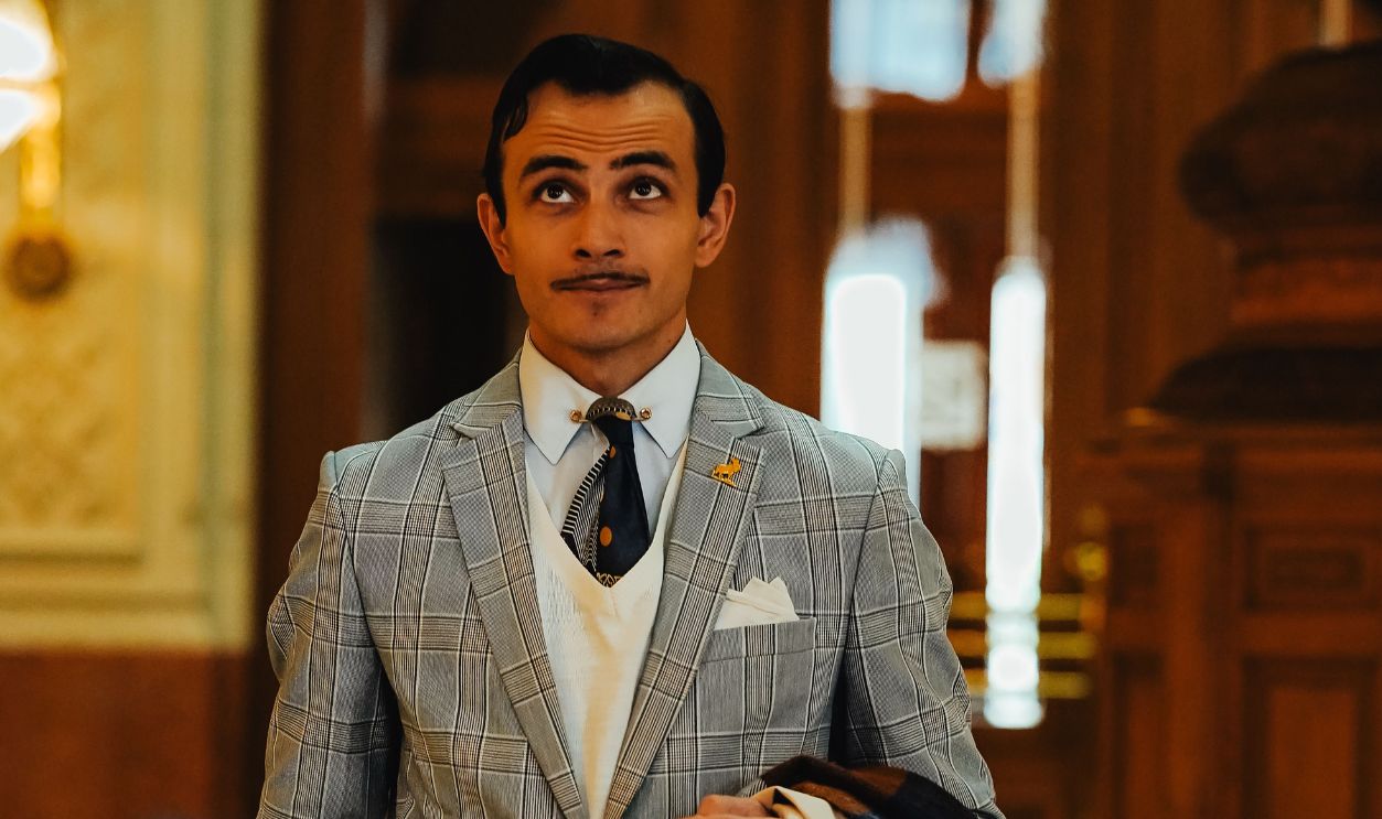 Man in a stylish suit with mustache standing in an elegant hotel lobby in Ankara, Turkiye