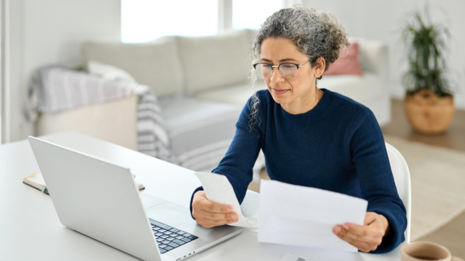 Mature lady paying bills online checking medical invoices receipts bills