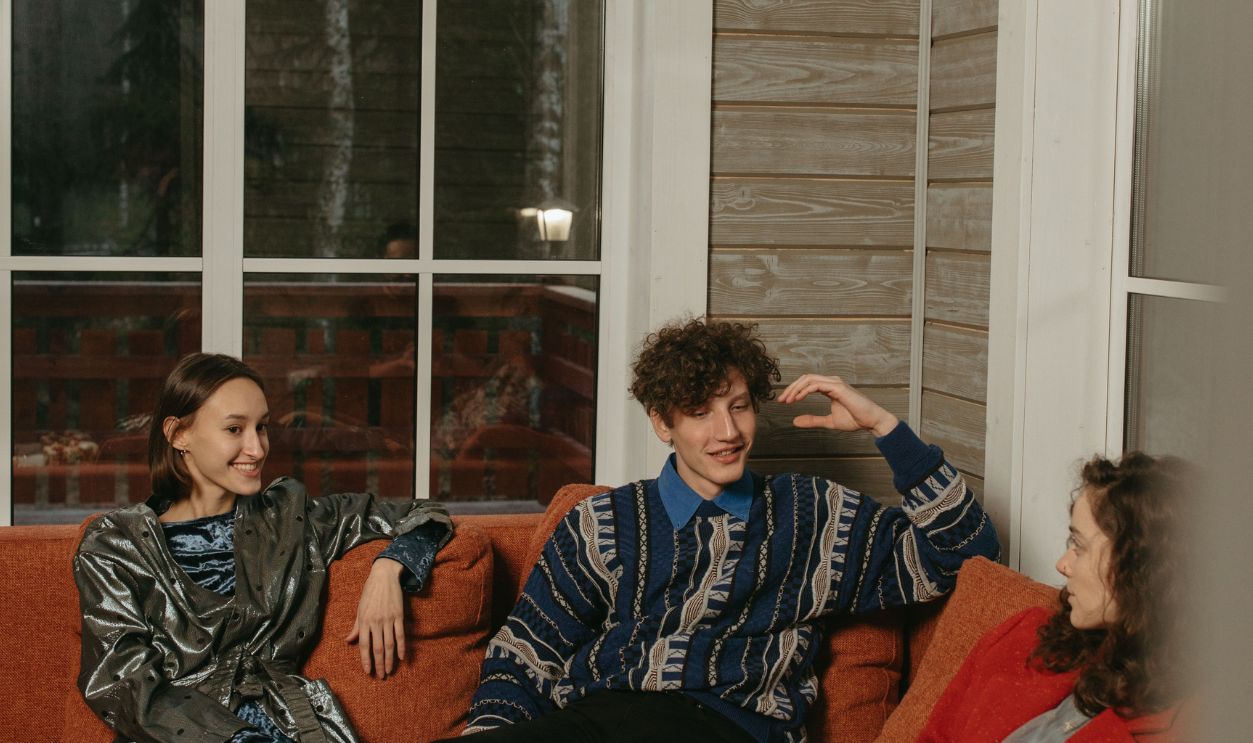 Three adults chatting in a cozy cabin interior with a warm atmosphere.