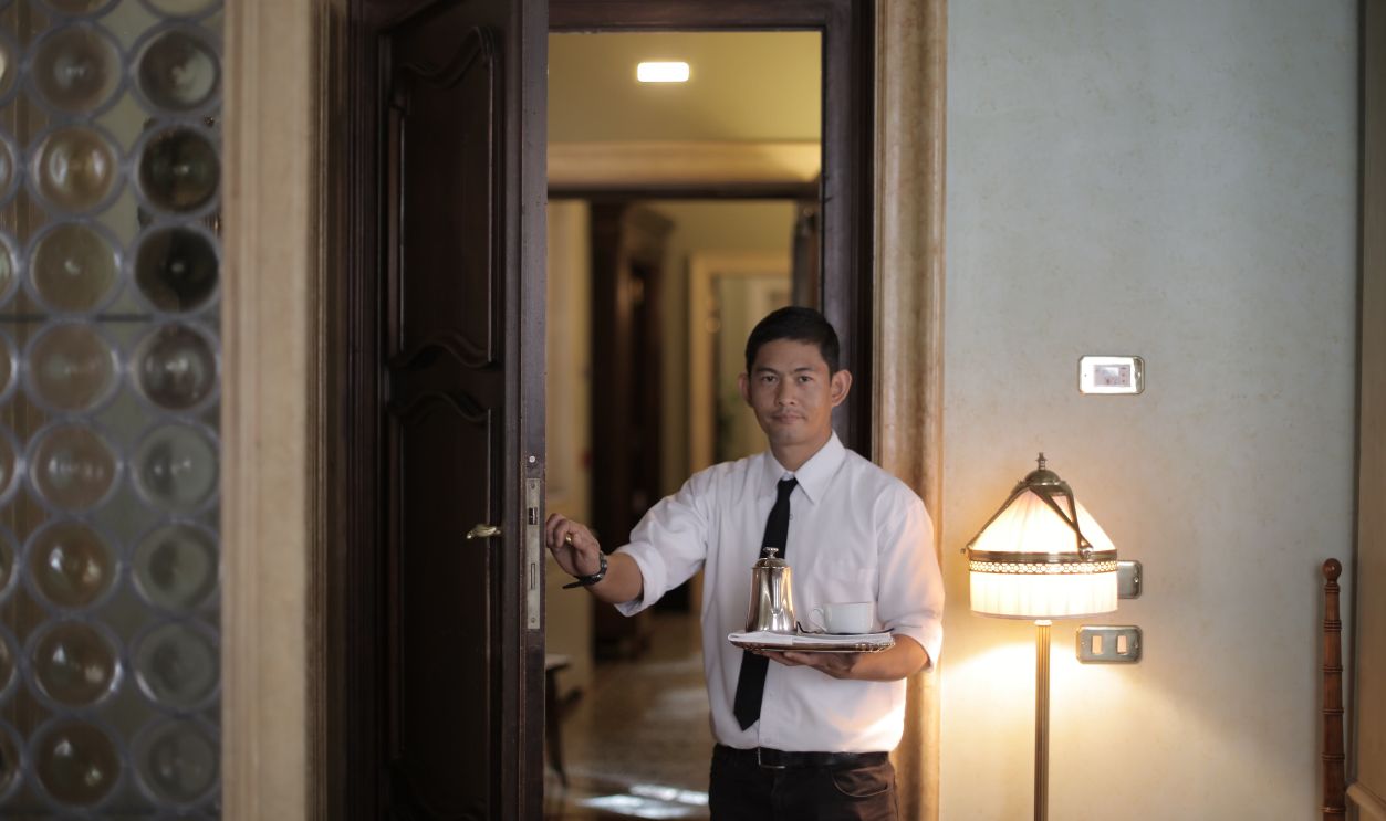 Elegant hotel room service presentation by a professional waiter at the doorway