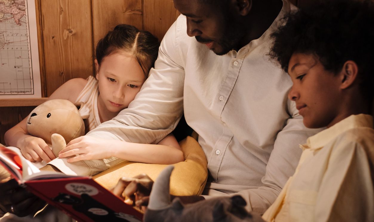 Father reading a bedtime story to his son and daughter, creating a cozy family moment