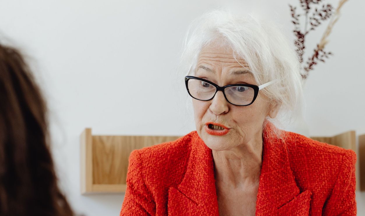 Senior businesswoman in a red blazer engaging in a professional meeting at the office
