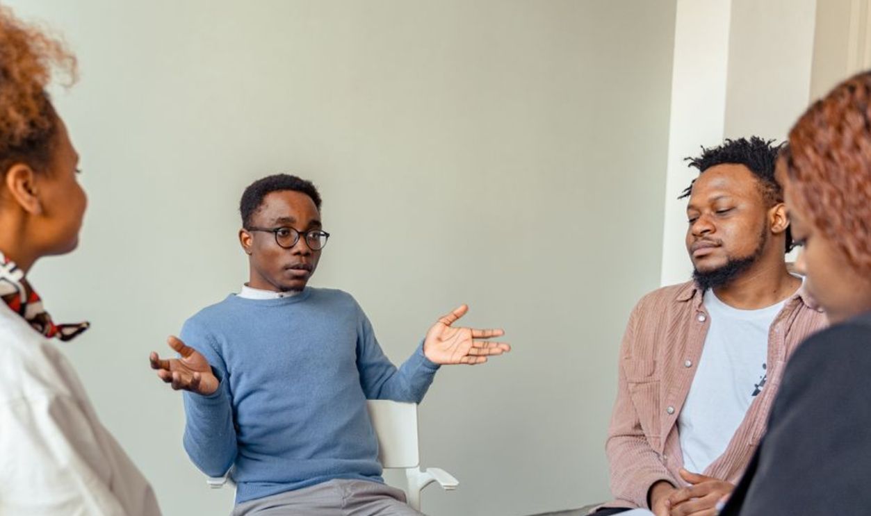 Diverse group therapy session with young adults and a mental health professional indoors