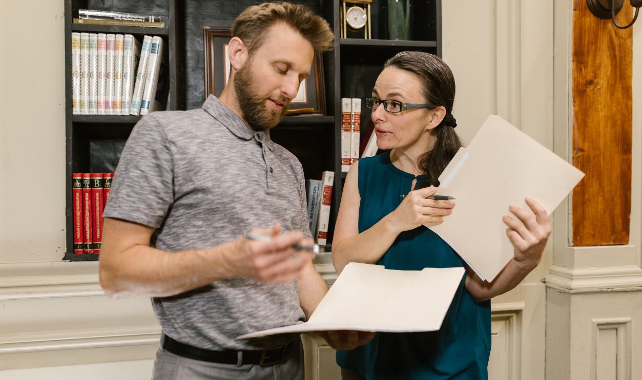 Two colleagues discussing work documents in a professional office setting