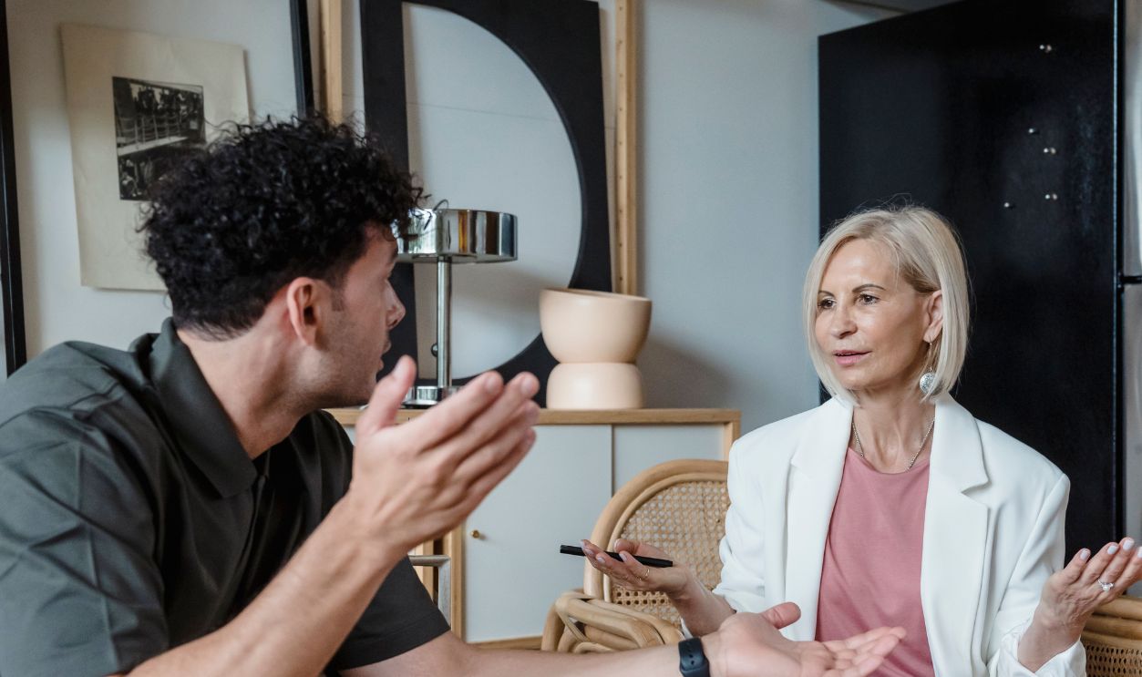 Two adults engaged in a lively discussion in a stylish indoor setting, illustrating communication and connection