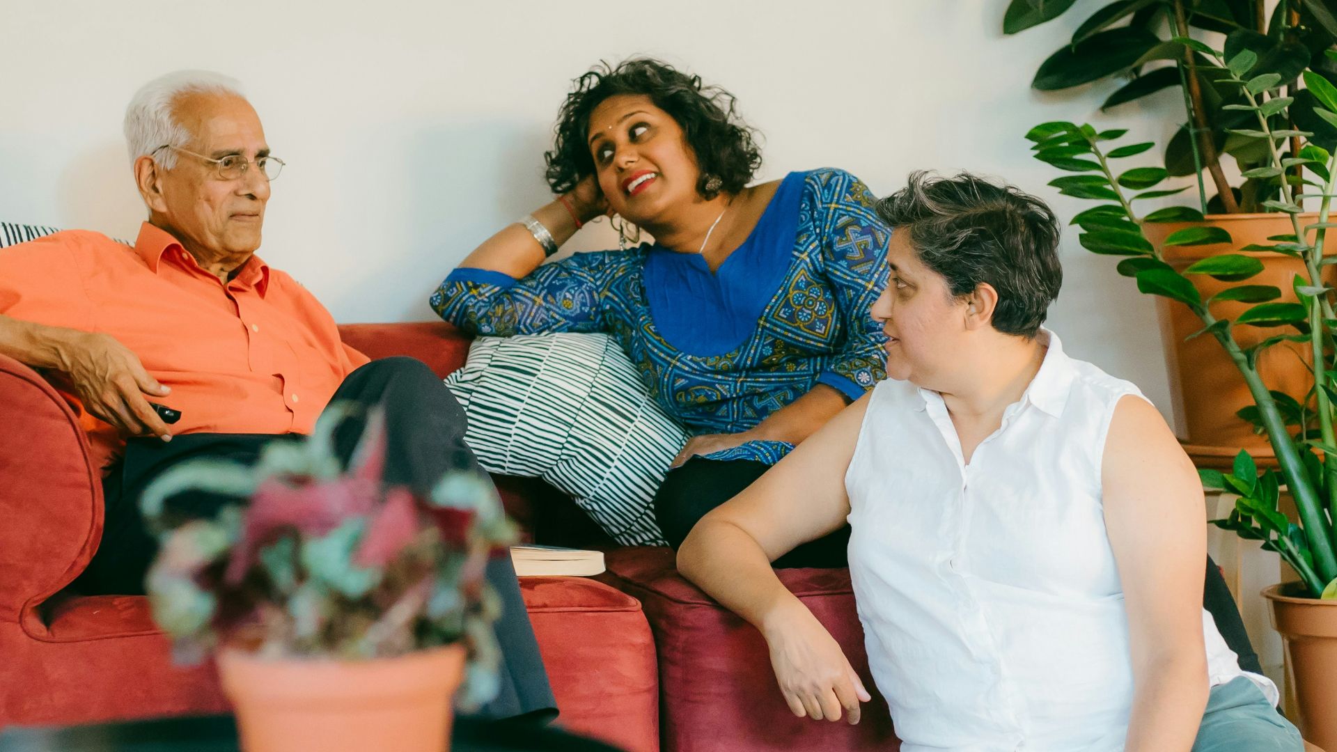 a woman sitting on top of a red couch next to a man