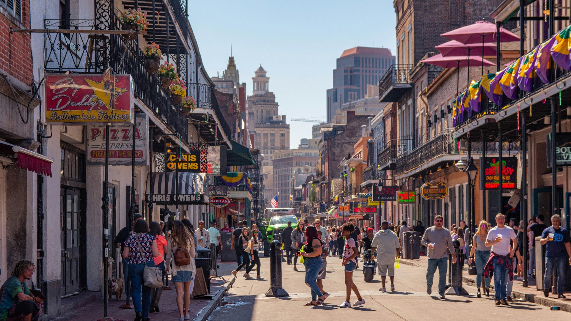 a group of people walking down a street next to tall buildings