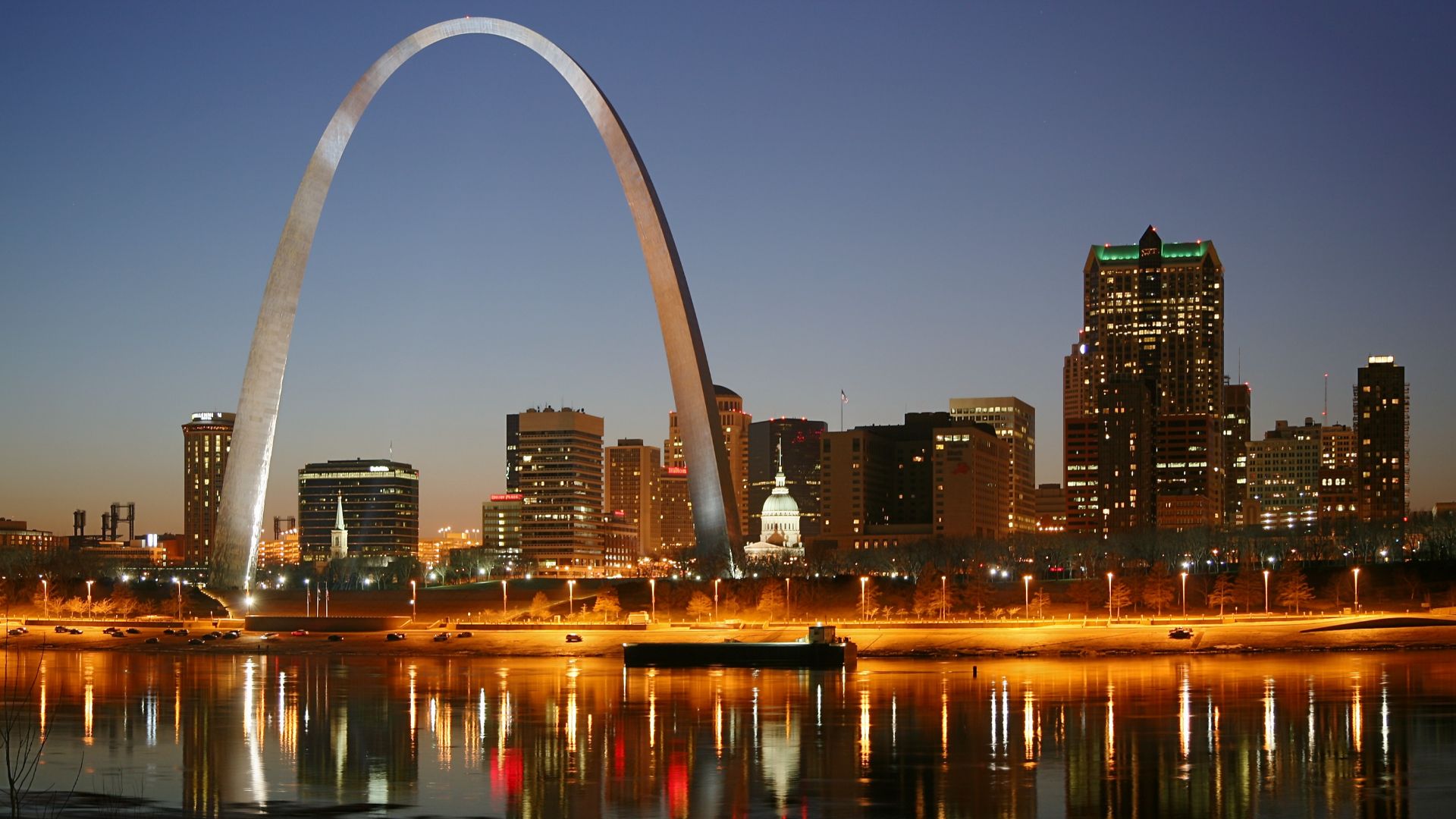 St. Louis on the Mississippi river by night. Jefferson National Expansion Memorial aka. Gateway Arch and Old Courthouse are visible.