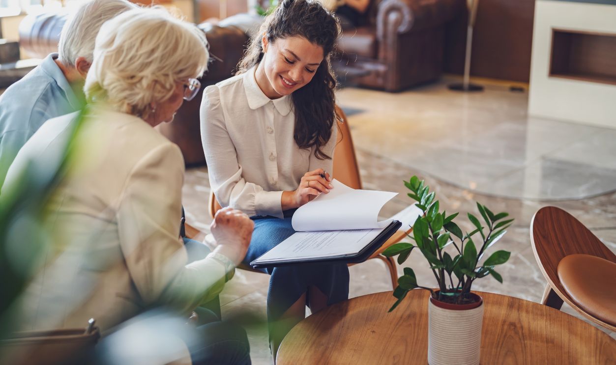 Shutterstock-2382621609, A hotel or travel agency representative is talking with a senior tourist couple offering various tourist services