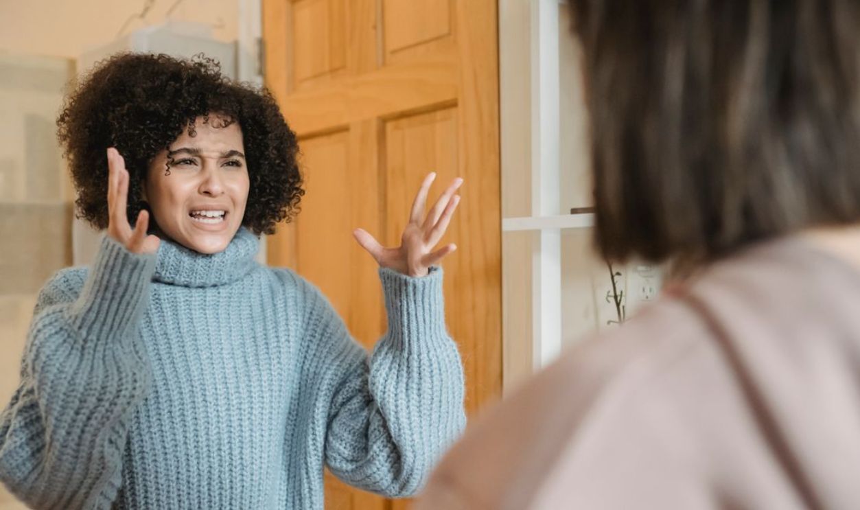 Two women engaged in an expressive and intense conversation indoors, showcasing strong emotions