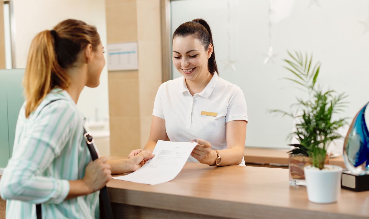 Shutterstock-1829155193, Happy massage therapist communicating with a customer at reception desk at the spa.