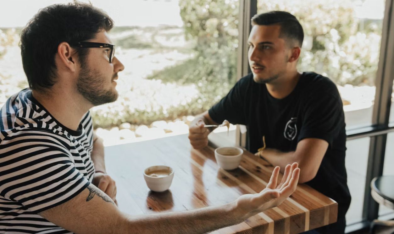 two men having conversation on table