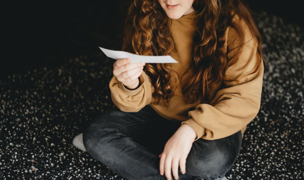woman in brown long sleeve shirt and blue denim jeans sitting on black and white textile