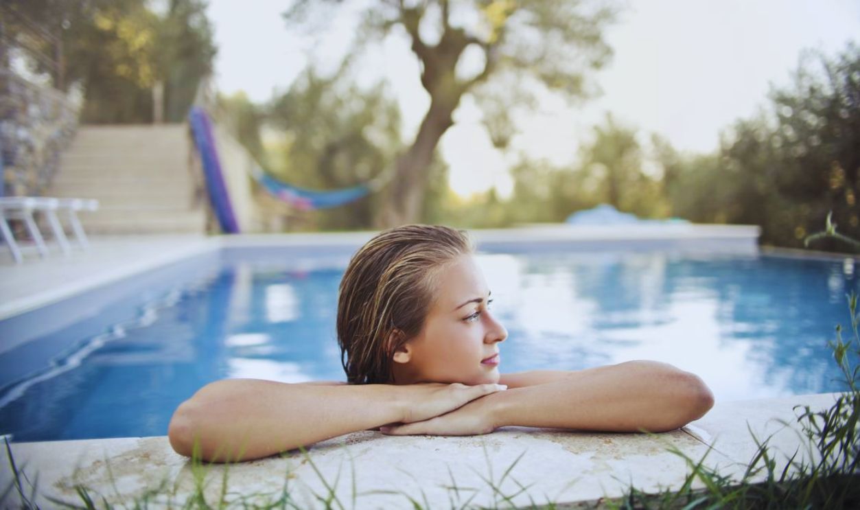 A serene moment of a woman relaxing at the edge of a pool, reflecting a peaceful summer day